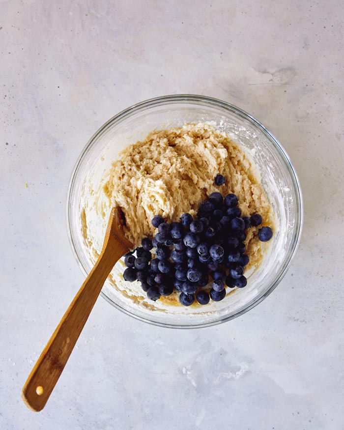 Blueberries poured into a bowl to fold into a batter. 