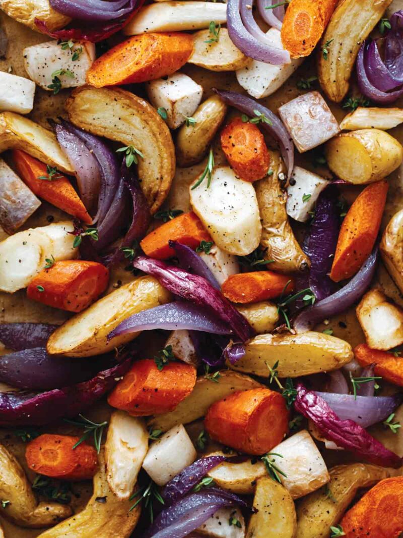 A close up of a variety of aromatic roasted root vegetables.