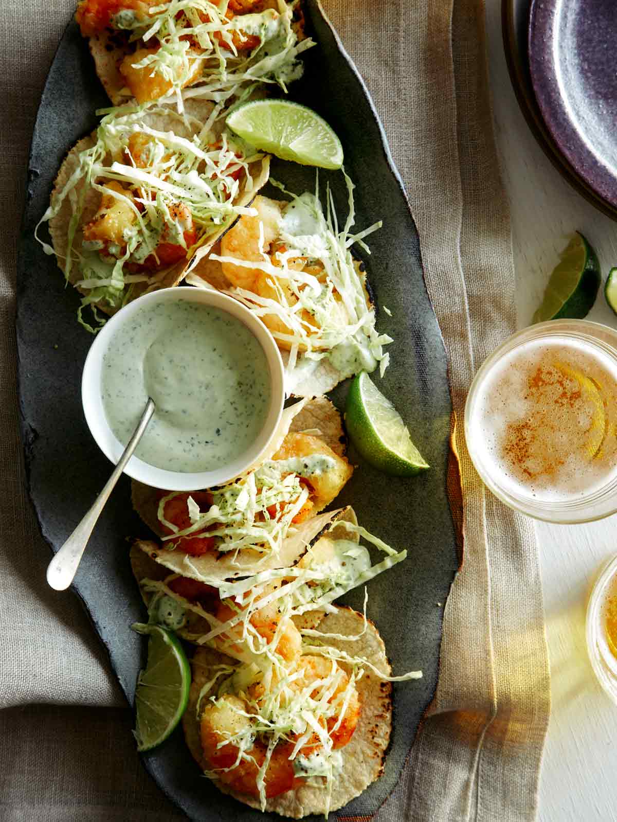 Beer Battered Shrimp Tacos on a platter with beer nearby. 