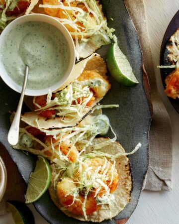 Beer battered shrimp tacos with lime wedges and a side of cilantro lime crema.