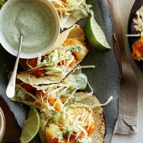 Beer battered shrimp tacos with lime wedges and a side of cilantro lime crema.