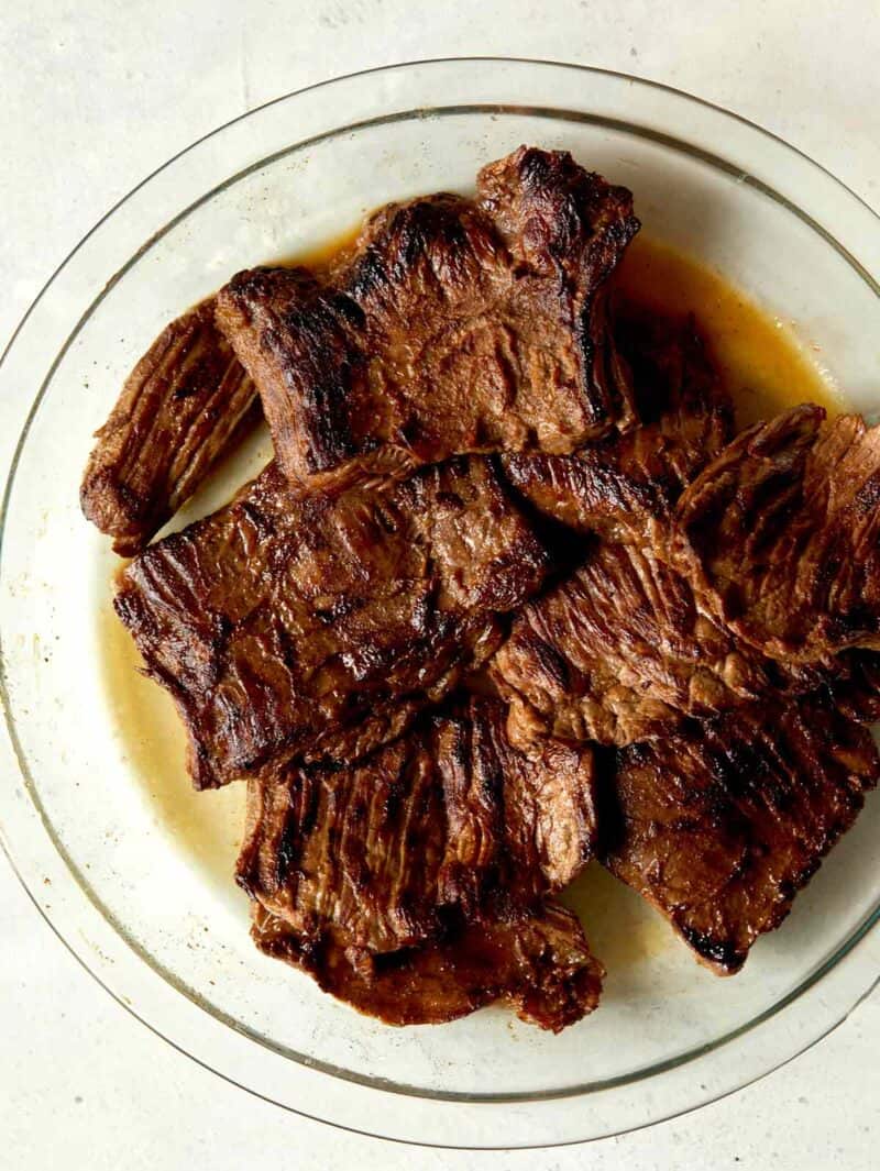 Freshly grilled carne asada in a glass dish.