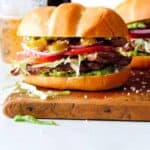 Carne Asada Torta on a wood cutting board with a beer in the background.