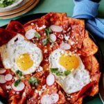 Chilaquiles in a skillet with plates next to it.