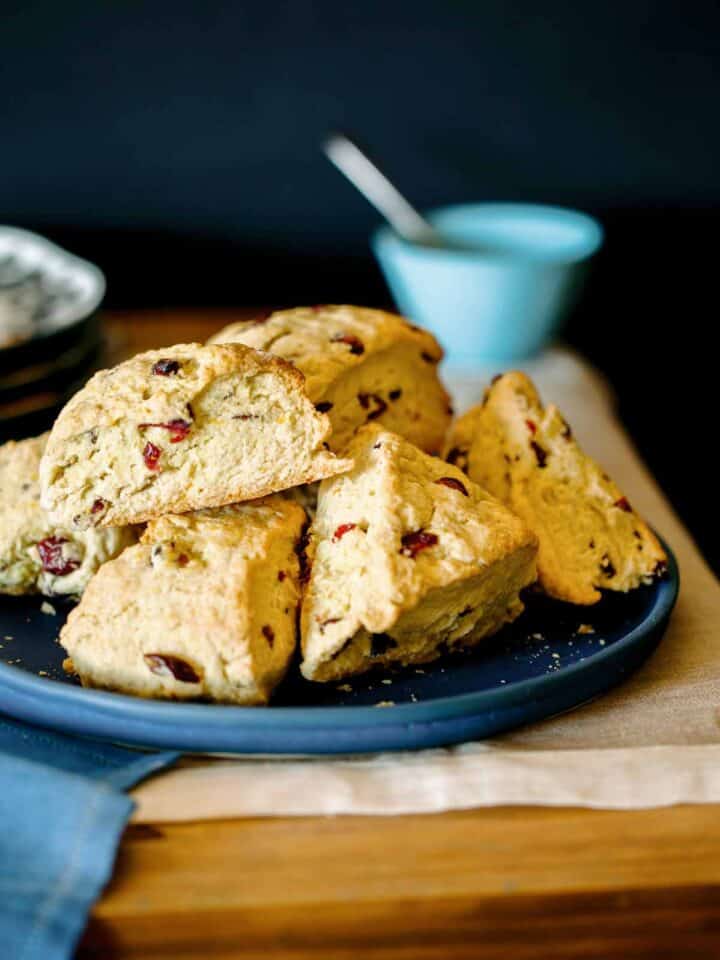 A close up of a pile of cranberry orange scones on a blue plate.