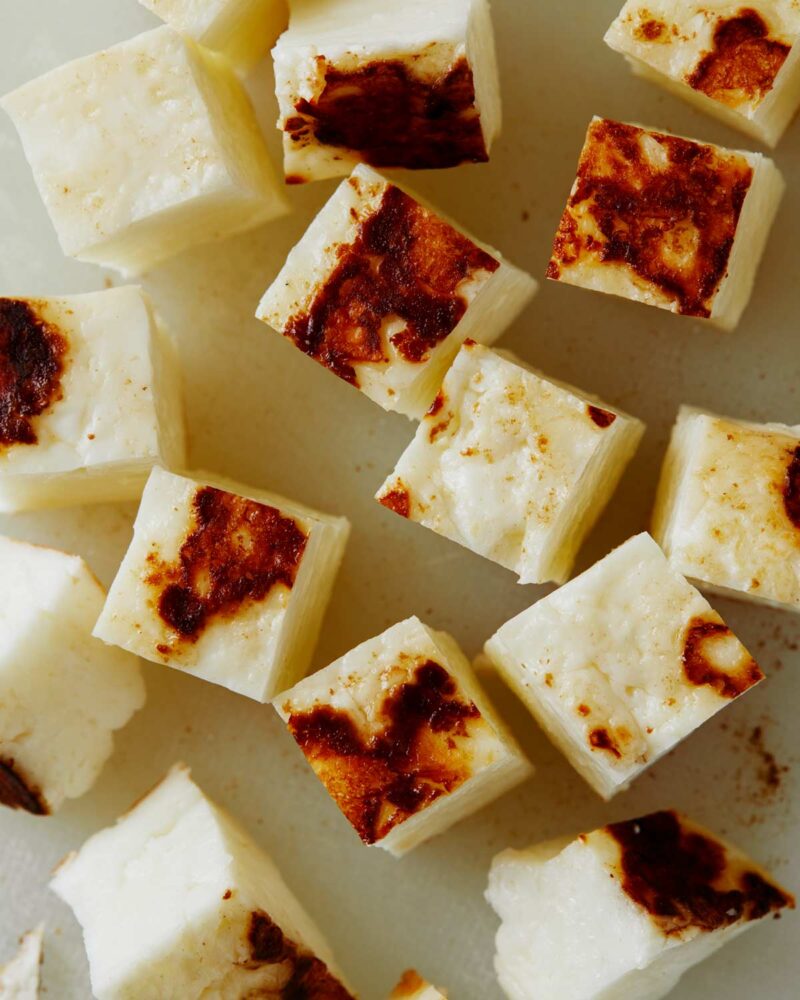 Cubed seared halloumi on a cutting board for a corn salad.