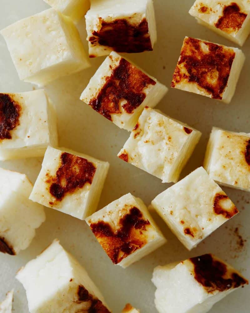 Seared halloumi cubed on a cutting board.