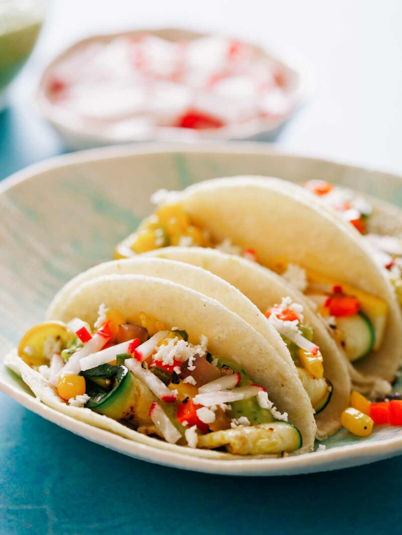 Vegetarian grilled zucchini tacos on a plate with radishes.