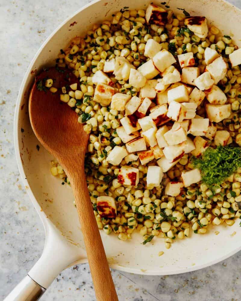 Summer corn halloumi salad with lime zest in a skillet. 