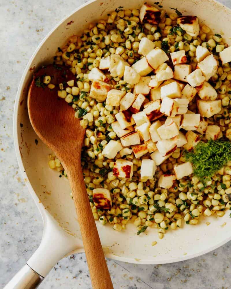 Summer corn halloumi salad with lime zest in a skillet.