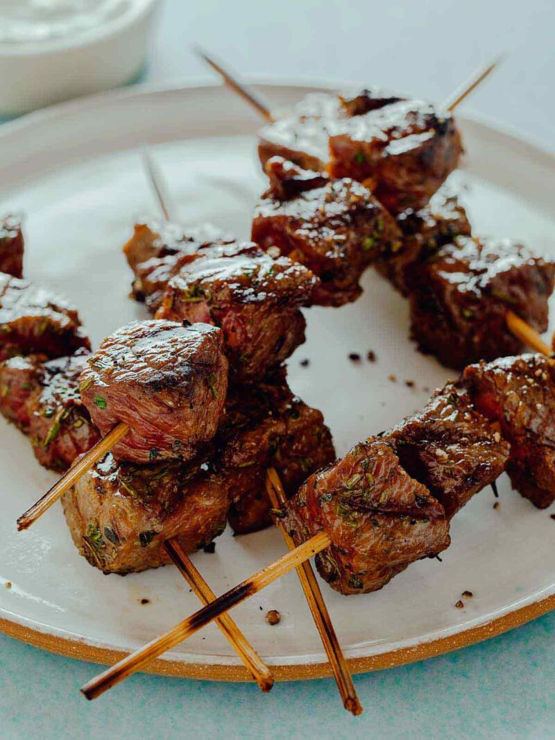 A close up of several criss crossed lamb kebabs on a plate.