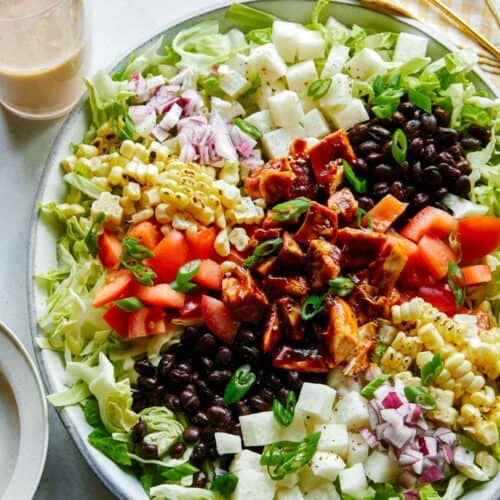 Loaded BBQ chicken salad on a plate with dressing on the side.