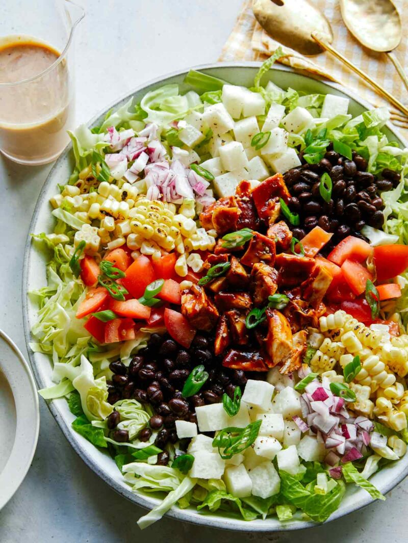 Summer bbq chicken salad recipe in a big bowl with dressing on the side. 