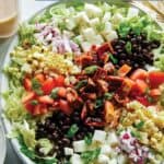 Loaded BBQ chicken salad on a plate with dressing on the side.