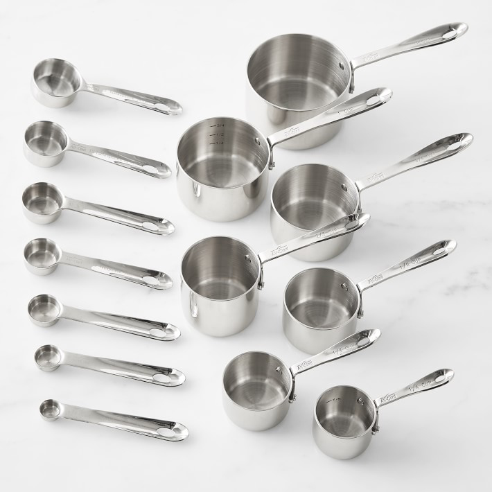 Set of measuring spoons and measuring cups laid out vertically from largest to smallest.