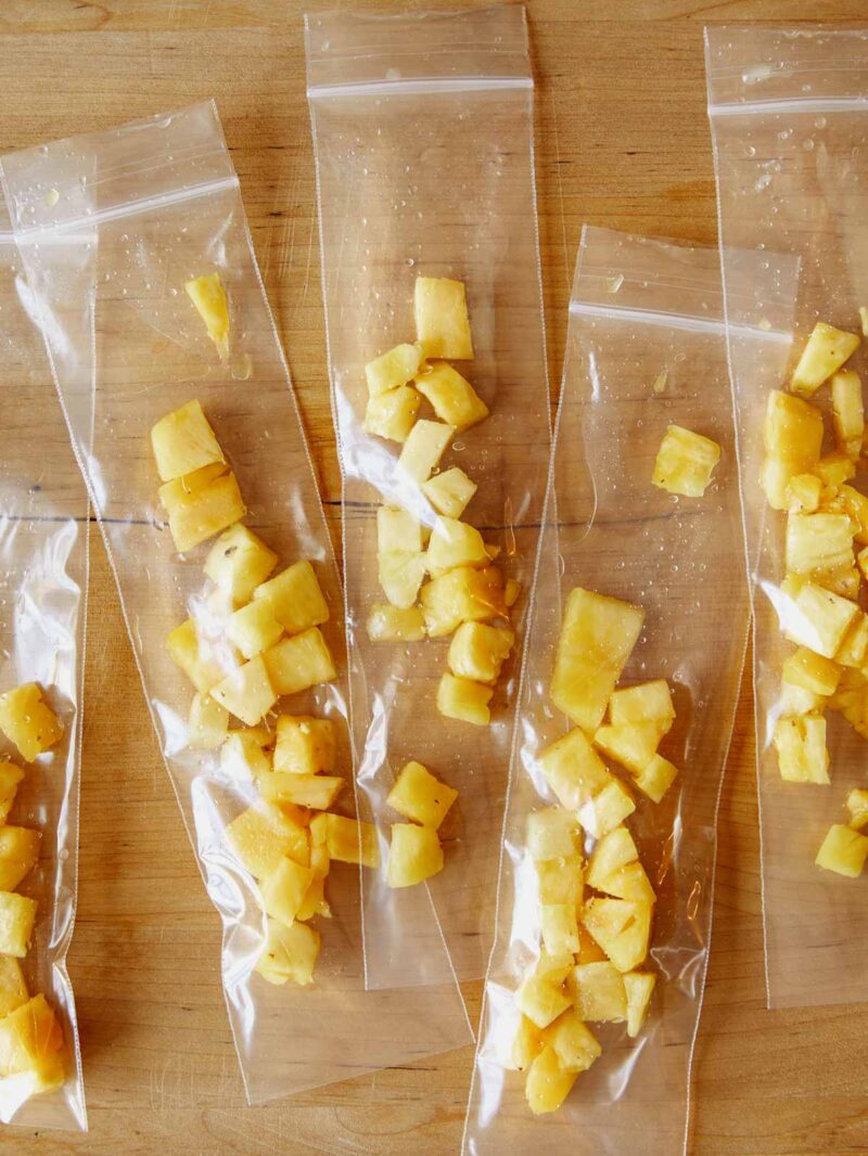 Pineapple chunks in ice pops sleeves ready for filling. 