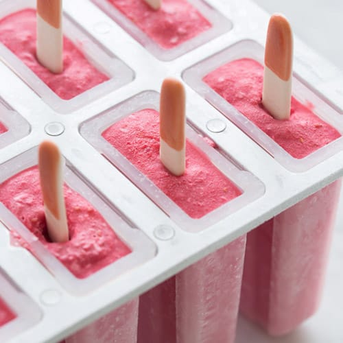 A close up of raspberry coconut popsicles in a popsicle mold.