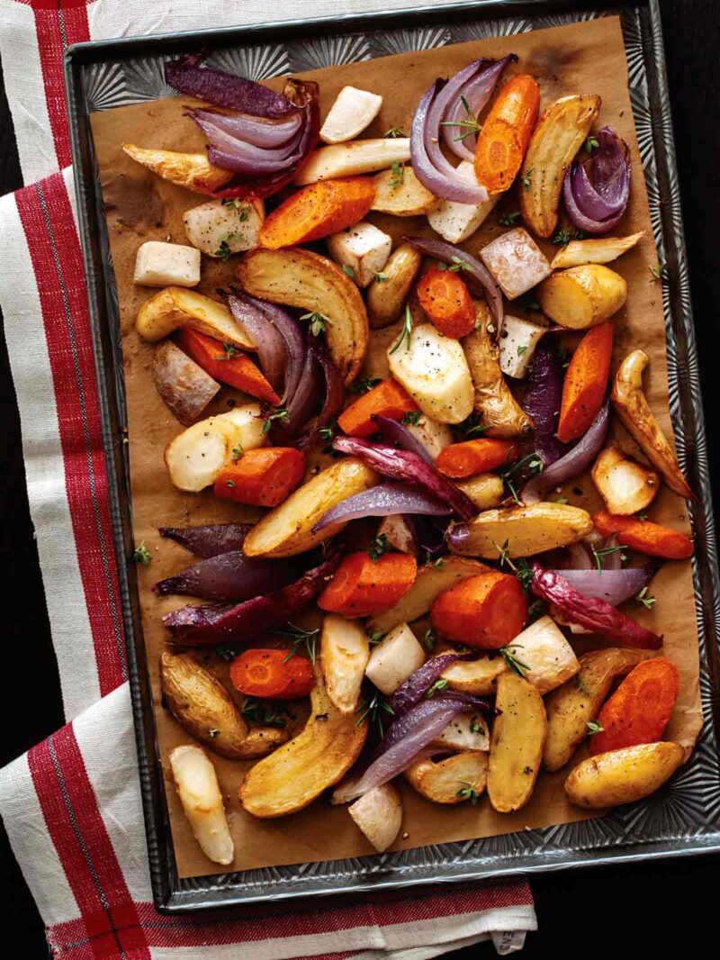 Aromatic roasted root vegetables on a sheet pan, overhead.
