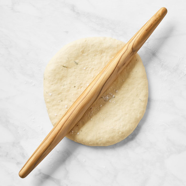 Wooden rolling pin on flattened dough.