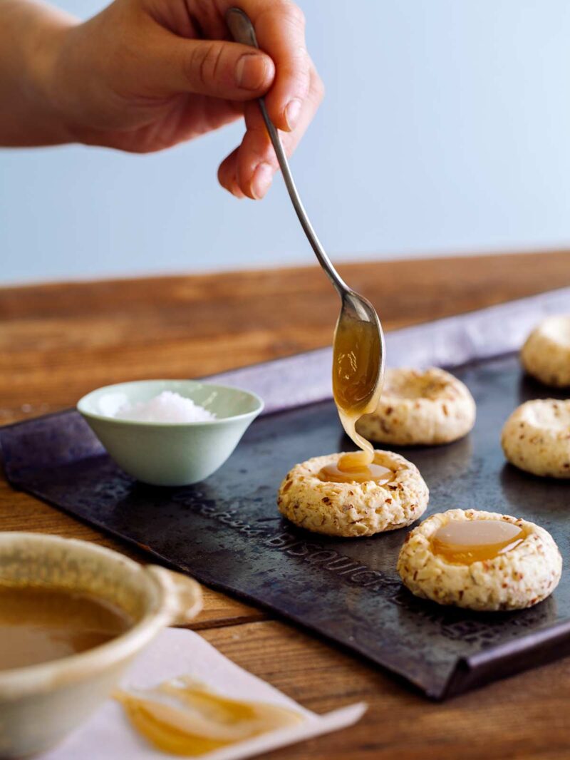 Filling the center of almond thumbprint cookies with caramel.