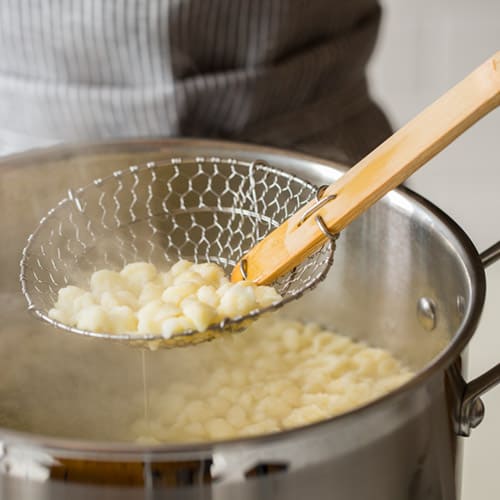 Cooked spaetzle strained out of a pot.