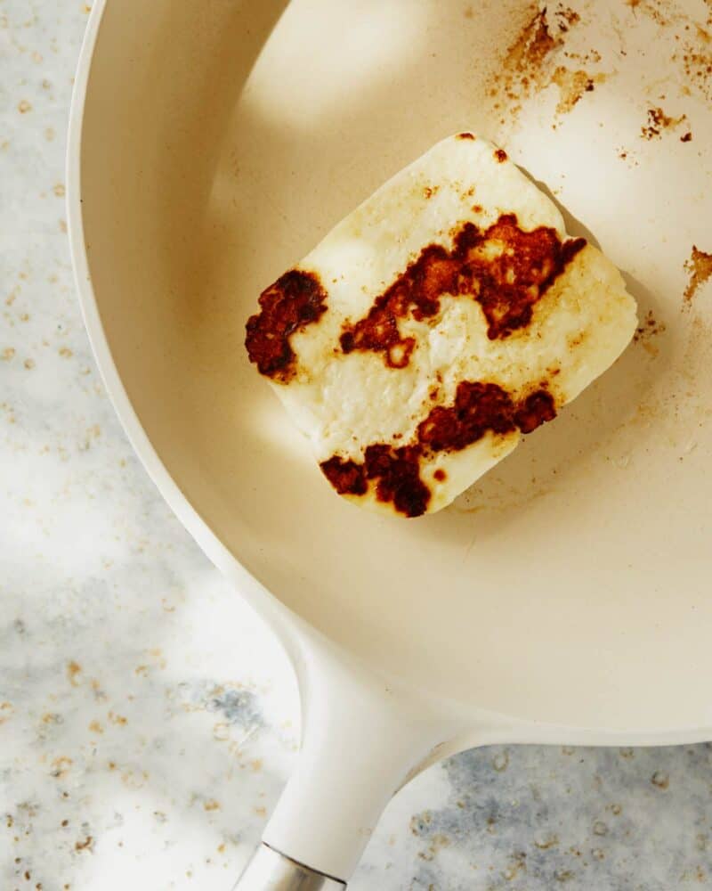 A close up of seared halloumi in a skillet.