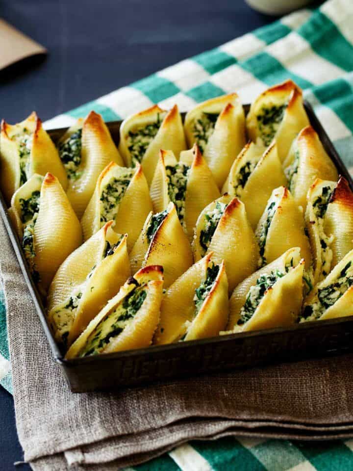 A close up of a pan full of spinach ricotta stuffed shells.