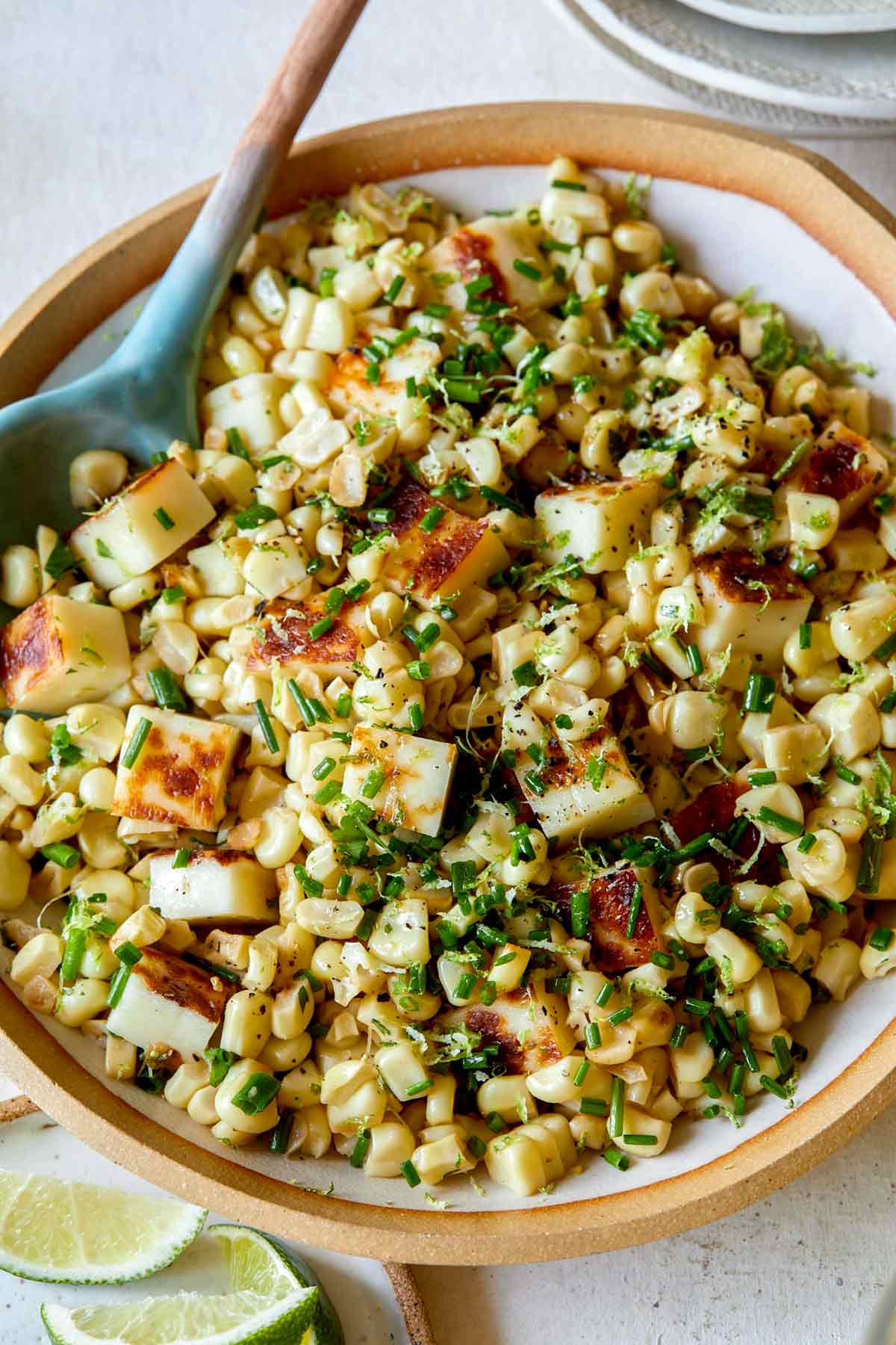 A close up on a summer corn halloumi salad with fresh herbs on top.