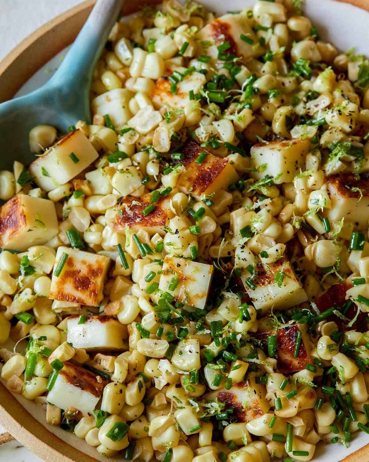 Summer corn halloumi salad in a bowl with a spoon.
