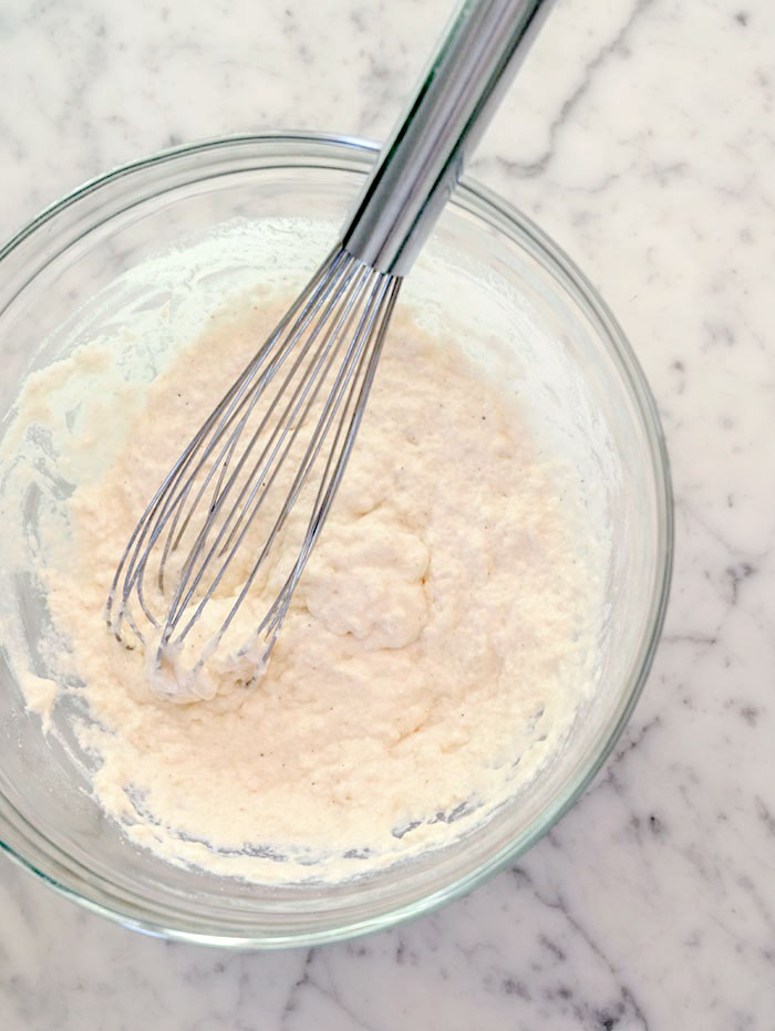 A bowl of the dry ingredients mixed with seltzer water with a whisk in the bowl.