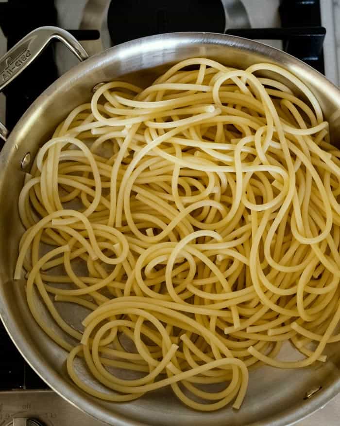 Cooked bucatini noodles in a skillet.