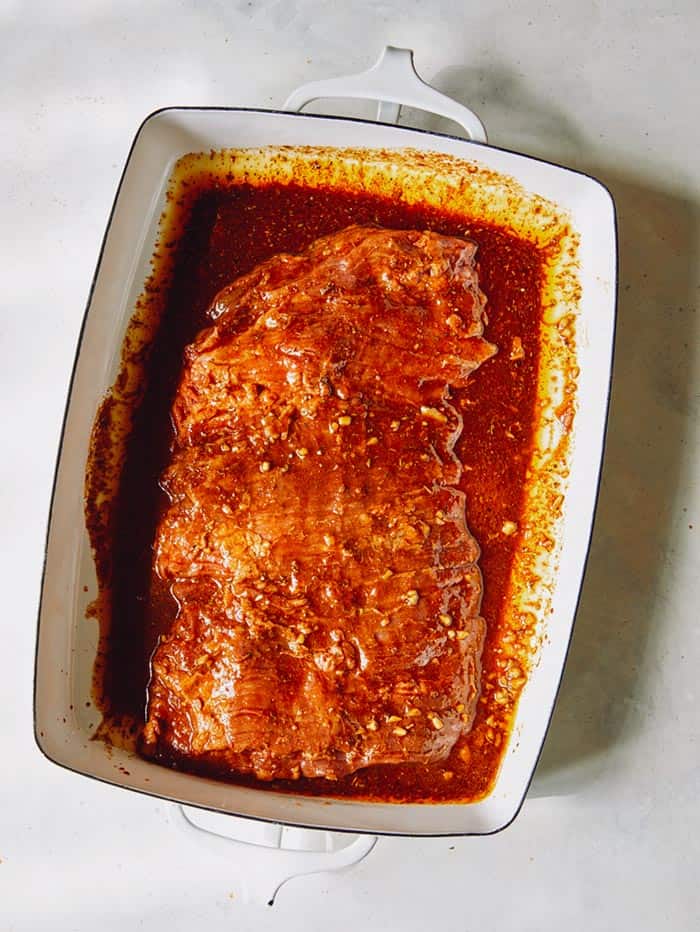 Marinated skirt steak in a shallow baking dish overhead.