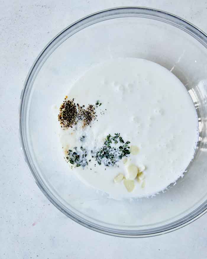 A bowl of buttermilk and other ingredients to soak the slices potatoes in. 