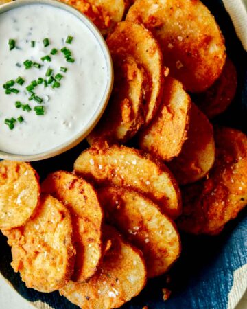 A close up of chicken fried potatoes with a ramekin of buttermilk ranch dipping sauce.