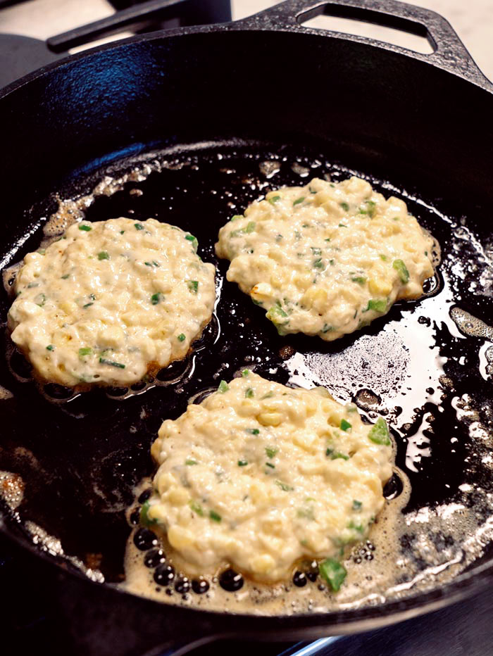 Corn cake batter in a skillet cooking with butter.