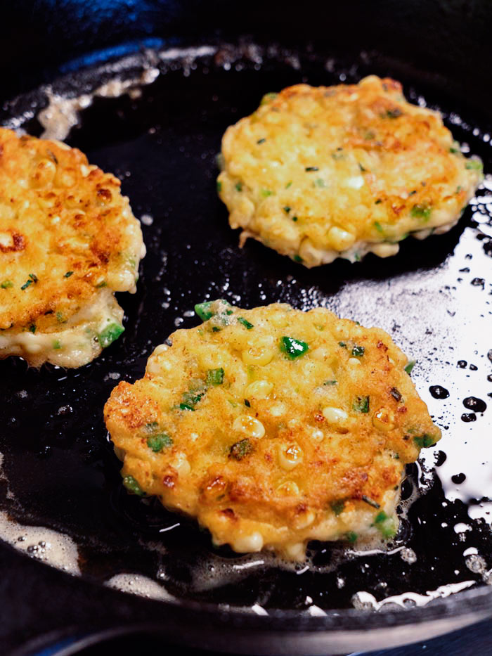 Corn cakes in a skillet after being flipped.