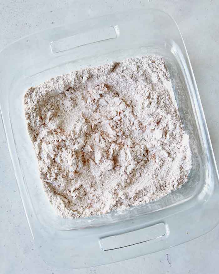 Buttermilk mixed together in the dredging ingredients in a shallow baking dish.
