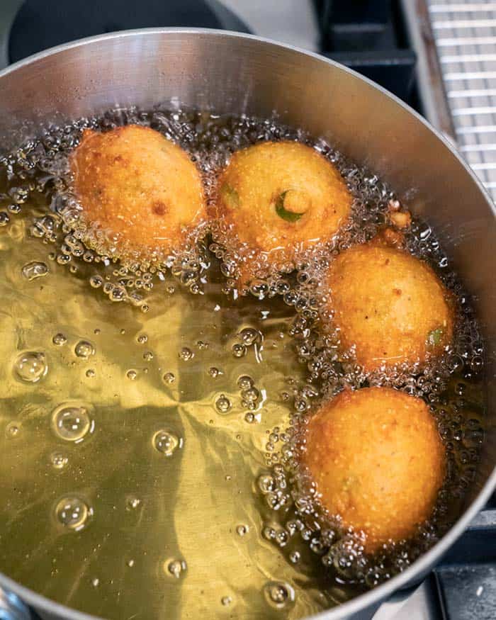 Hush Puppies finishing up frying in a pot of hot oil.