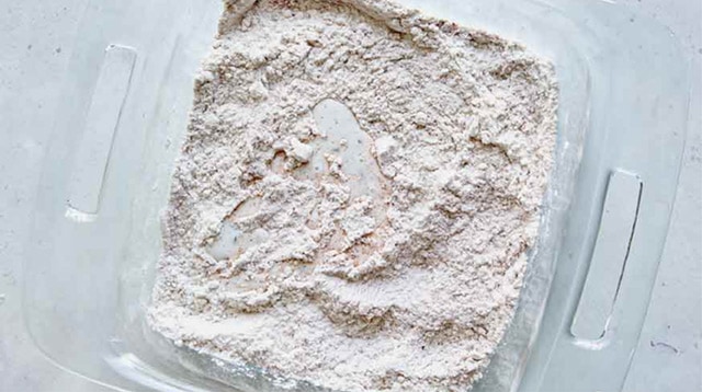Some buttermilk spooned into a glass dish with flour.