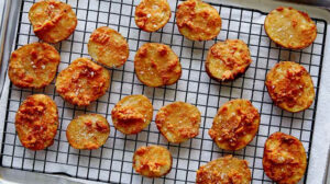 Chicken fried potatoes freshly fried and drying on a rack.