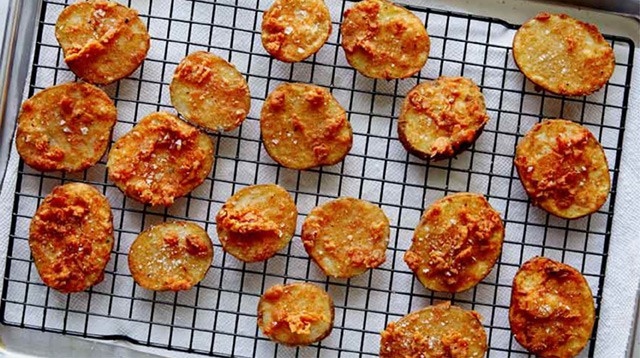 Chicken fried potatoes freshly fried and drying on a rack.