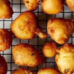 Hush puppies freshly fried on a baking sheet.