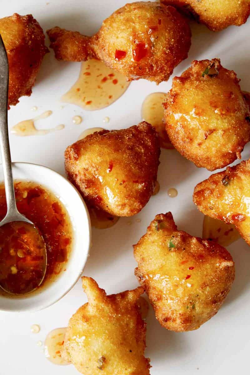 A close up of hush puppies drizzled with spicy honey.