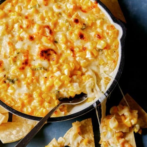 Korean cheese corn baked in a pan with spoon next to dipped chips and melted cheese, part of our Thanksgiving appetizers collection.