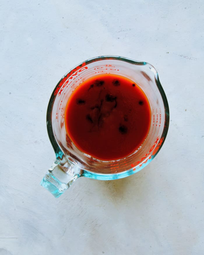 Adding ingredients for a Michelada in a measuring cup. 