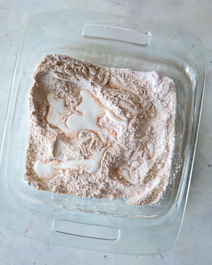 Spoon fulls of buttermilk drizzled into the baking dish with the dry ingredients.