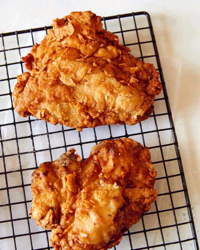 A close up of Popeyes Fried Chicken on a wire rack.