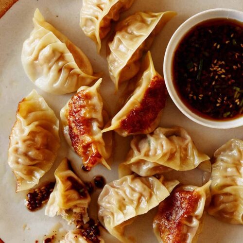 Panfried potstickers with ramekin of sauce.