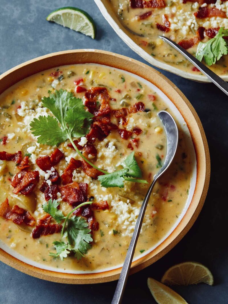 A close up of roasted corn chowder with a spoon.
