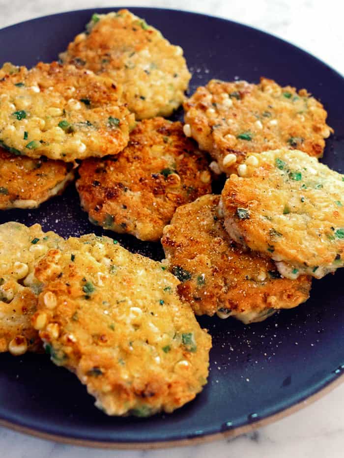 Corn cakes on a platter seasoned  with salt and pepper. 